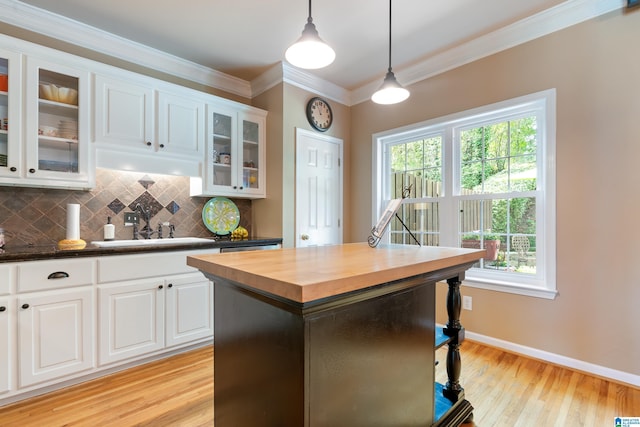 kitchen with wood counters, a sink, plenty of natural light, decorative backsplash, and crown molding
