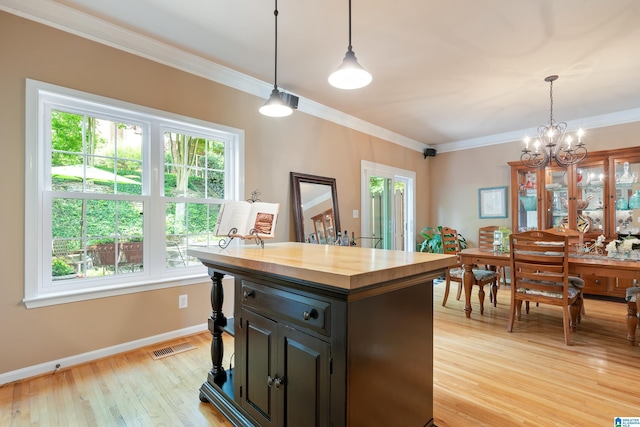 bar featuring light wood-type flooring, crown molding, a chandelier, baseboards, and hanging light fixtures