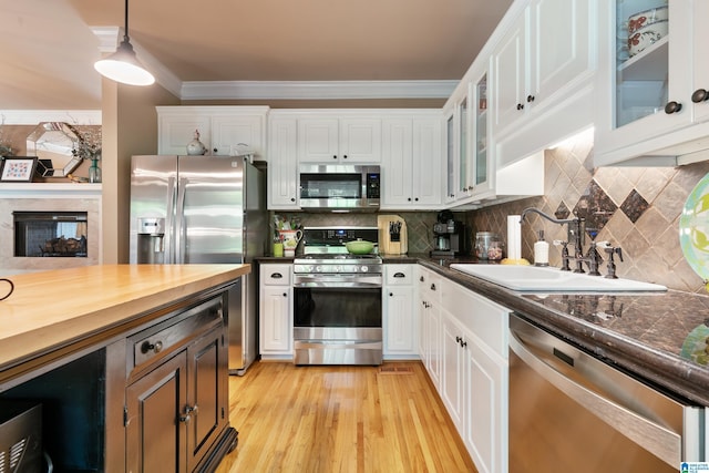 kitchen featuring stainless steel appliances, a sink, white cabinetry, pendant lighting, and backsplash