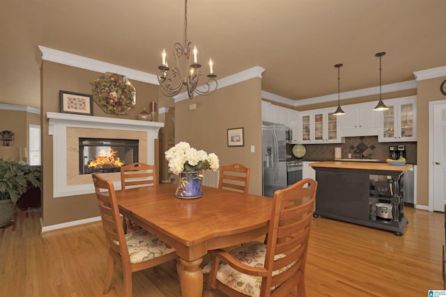 dining space featuring ornamental molding, light wood-type flooring, baseboards, a multi sided fireplace, and a chandelier