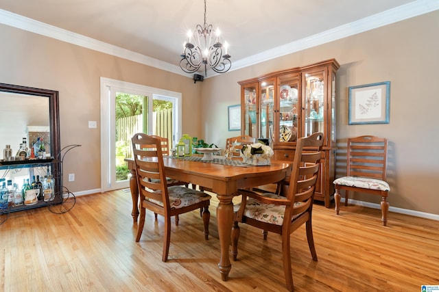 dining room featuring light wood-style flooring, a chandelier, baseboards, and ornamental molding
