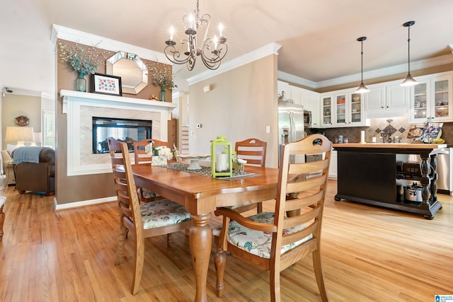 dining space featuring ornamental molding, light wood-style floors, a chandelier, a multi sided fireplace, and baseboards