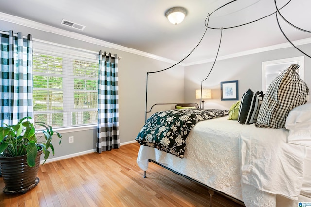 bedroom with hardwood / wood-style flooring, ornamental molding, and baseboards