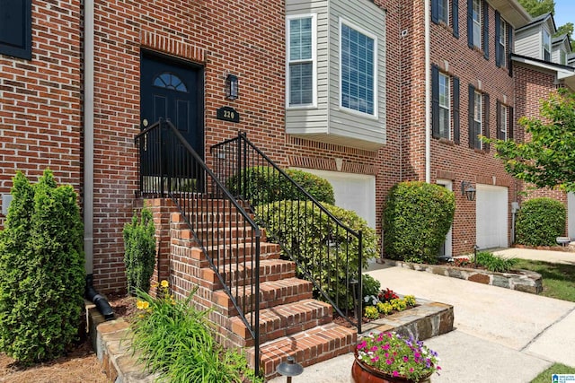 view of exterior entry featuring brick siding and a garage