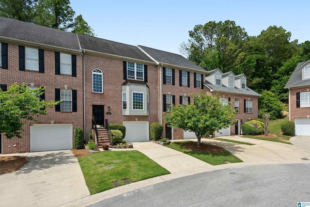 townhome / multi-family property featuring driveway, a garage, and brick siding