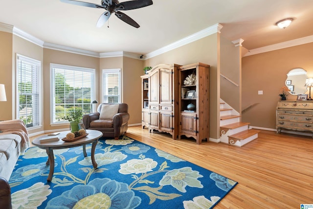 living area with light wood-style flooring, a ceiling fan, ornamental molding, stairway, and baseboards