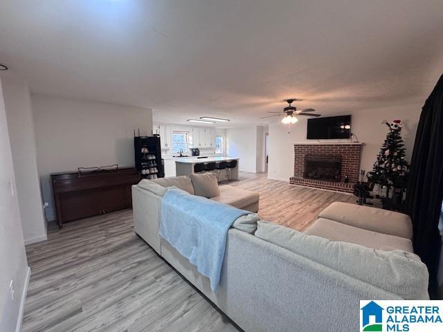 3585 County Road 26, Wadley, AL 36276 - living area featuring a ceiling fan, light wood finished floors, a brick fireplace, and baseboards