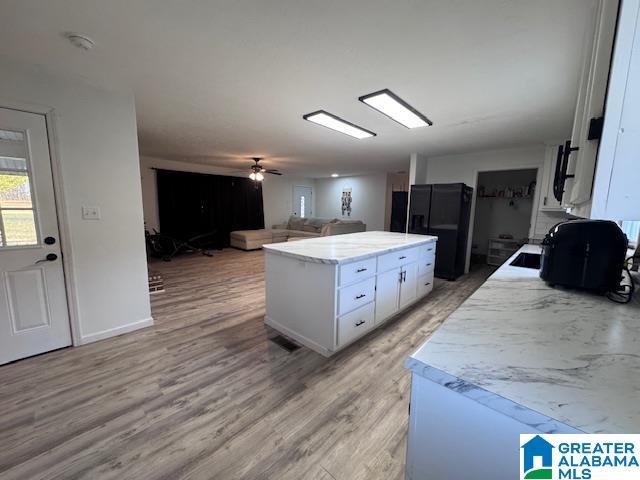 3585 County Road 26, Wadley, AL 36276 - kitchen with freestanding refrigerator, white cabinets, light wood-type flooring, a kitchen island, and open floor plan