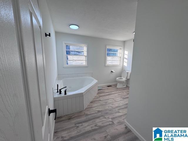 3585 County Road 26, Wadley, AL 36276 - full bathroom featuring toilet, a bath, wood finished floors, and baseboards