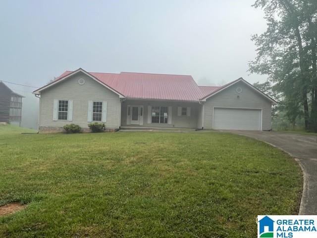 ranch-style home featuring driveway, an attached garage, a front yard, and metal roof