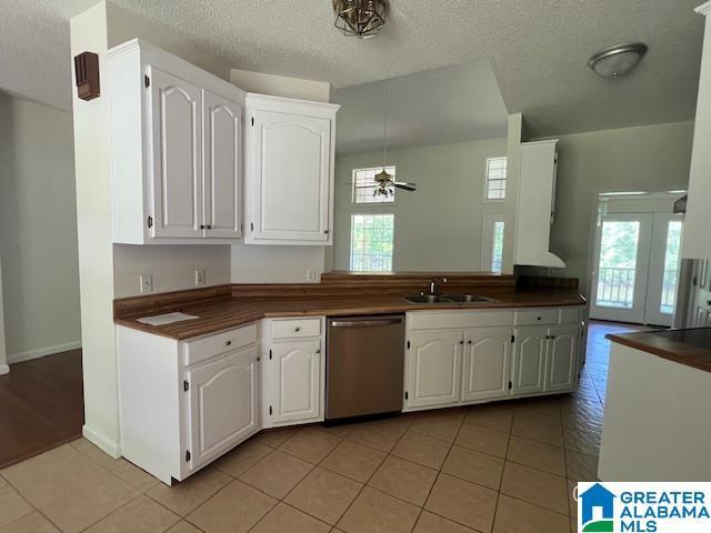 kitchen featuring dishwasher, dark countertops, a ceiling fan, a sink, and white cabinetry
