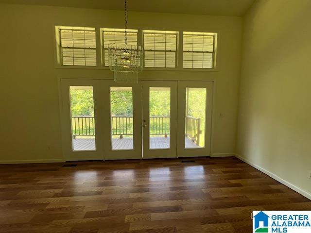 entryway featuring a chandelier, healthy amount of natural light, wood finished floors, french doors, and a high ceiling