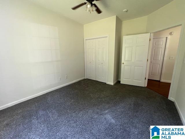 unfurnished bedroom with dark colored carpet, baseboards, a closet, a ceiling fan, and vaulted ceiling