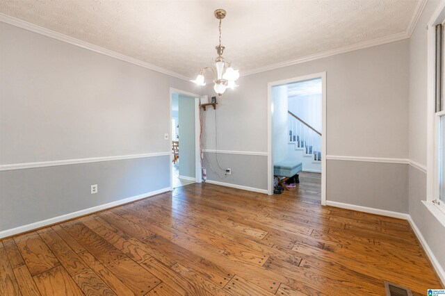 1201 Devonshire Dr NE, Jacksonville, AL 36265 - unfurnished room with a chandelier, wood finished floors, crown molding, baseboards, and stairs