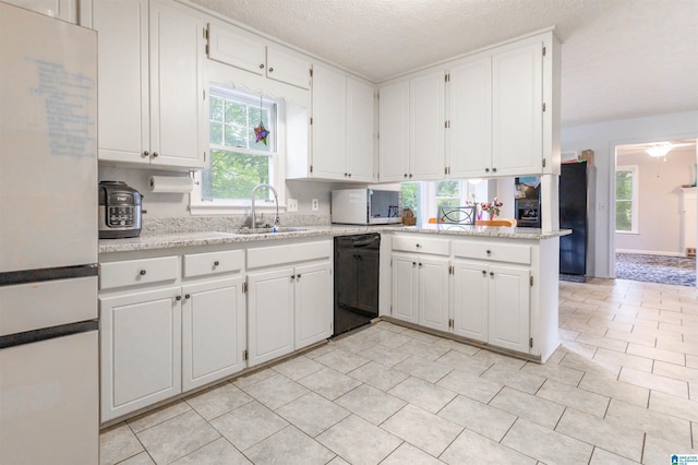 1201 Devonshire Dr NE, Jacksonville, AL 36265 - kitchen featuring freestanding refrigerator, dishwasher, a sink, stainless steel microwave, and white cabinetry