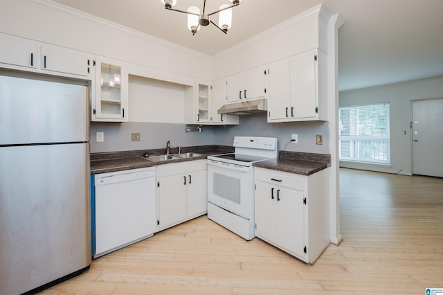 kitchen featuring white appliances, a sink, under cabinet range hood, a chandelier, and dark countertops