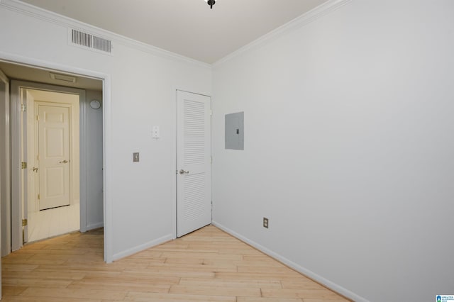 spare room with electric panel, ornamental molding, light wood-style flooring, and baseboards