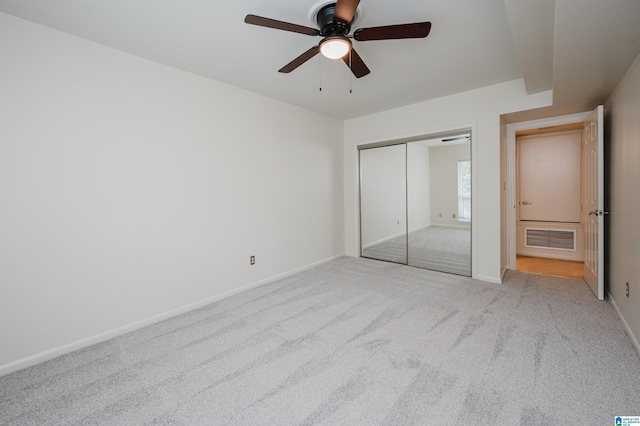 unfurnished bedroom with carpet flooring, a closet, baseboards, and ceiling fan