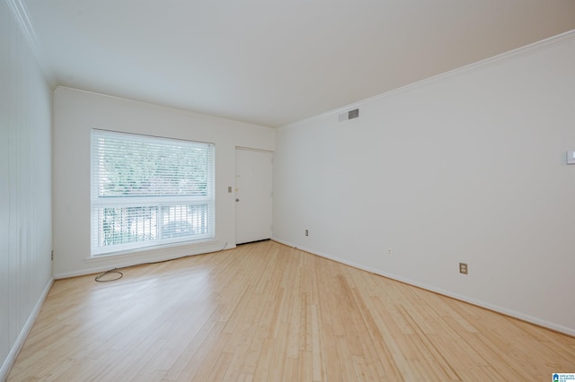 spare room with wood finished floors, crown molding, and baseboards