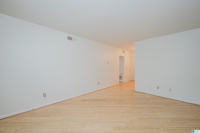 empty room featuring ornamental molding, light wood finished floors, and baseboards