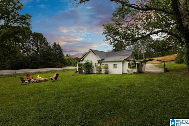 1034 Valley Rd, Oneonta, AL 35121 - property exterior at dusk with an outdoor fire pit, a yard, and metal roof