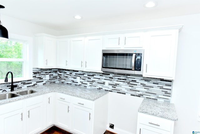 1545 32nd St, Birmingham, AL 35218 - kitchen with stainless steel microwave, a sink, light stone countertops, white cabinetry, and recessed lighting
