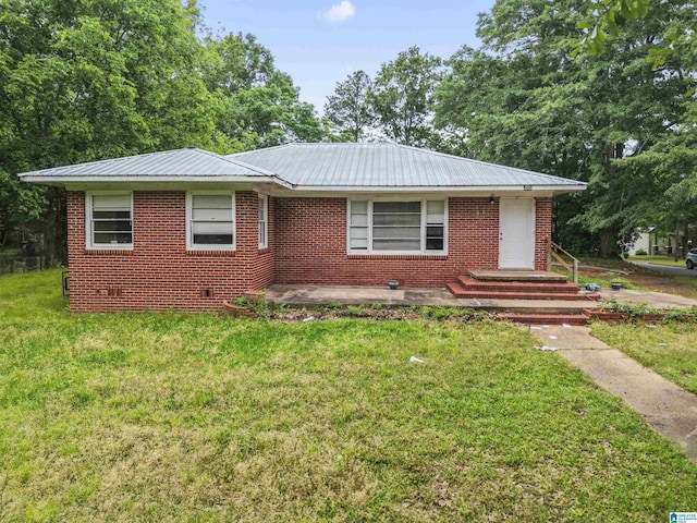 view of front of house featuring a front lawn, metal roof, and brick siding