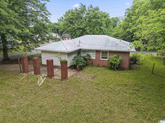 view of side of property with a yard, metal roof, and brick siding