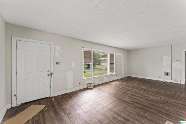 unfurnished living room featuring a textured ceiling, wood finished floors, and baseboards