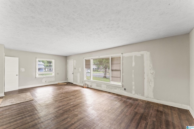 unfurnished living room featuring wood finished floors, baseboards, and a textured ceiling
