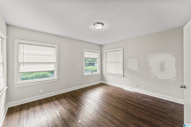 unfurnished room featuring plenty of natural light, wood finished floors, and baseboards