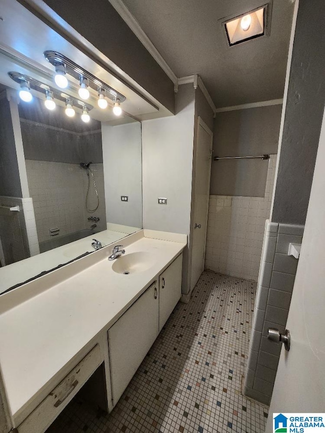 bathroom featuring tiled shower, crown molding, vanity, and tile patterned floors