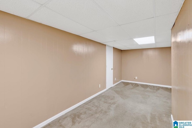 finished basement featuring a drop ceiling, carpet, and baseboards