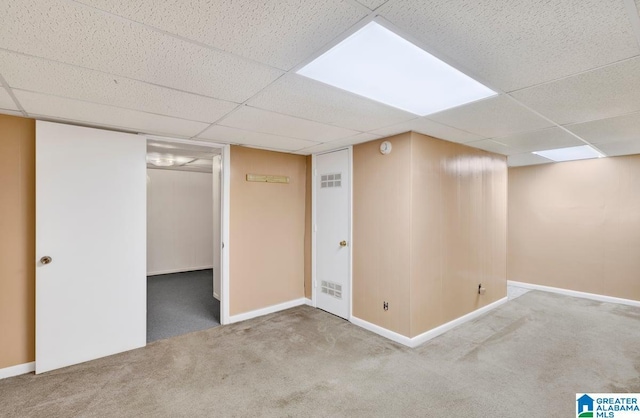 finished below grade area featuring carpet floors, a paneled ceiling, and baseboards