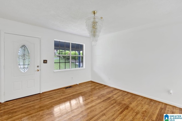 entryway featuring a chandelier, wood finished floors, and baseboards