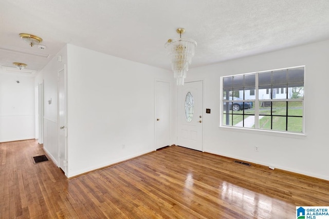 entrance foyer featuring wood finished floors, a chandelier, and baseboards
