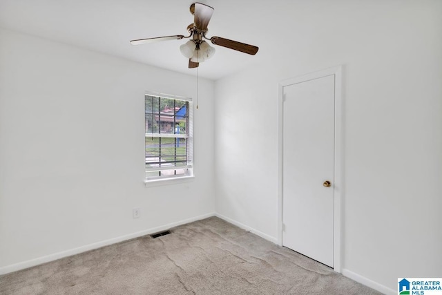 carpeted empty room featuring a ceiling fan and baseboards