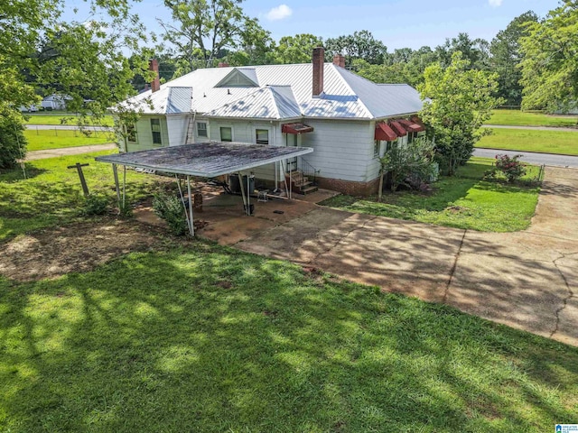 315 W Parkway Ave, Talladega, AL 35160 - rear view of house with a chimney, concrete driveway, a lawn, metal roof, and a carport