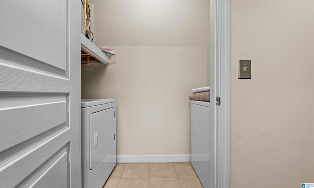 clothes washing area with washing machine and clothes dryer, light tile patterned floors, and baseboards