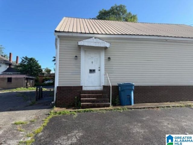 view of front of house featuring entry steps, brick siding, and metal roof