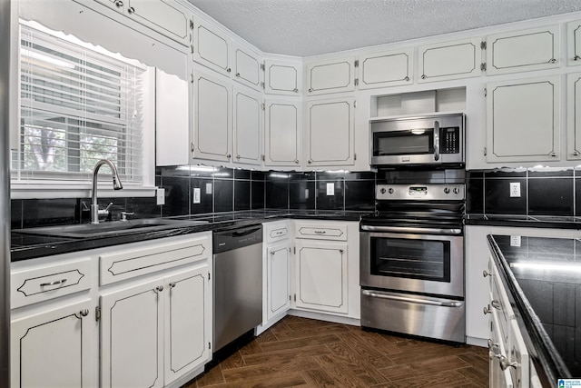 402 S 8th St, Gadsden, AL 35901 - kitchen featuring appliances with stainless steel finishes, a sink, dark countertops, white cabinets, and a textured ceiling