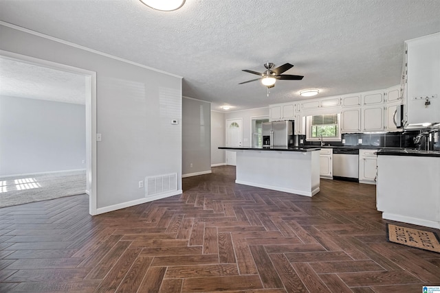 402 S 8th St, Gadsden, AL 35901 - kitchen featuring appliances with stainless steel finishes, a ceiling fan, a center island, dark countertops, and a textured ceiling