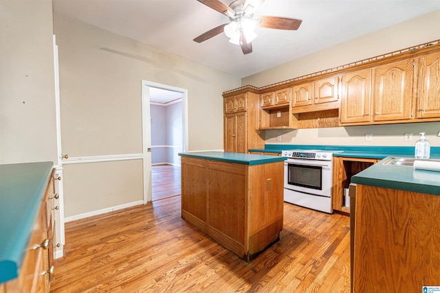 kitchen with white range with electric cooktop, a center island, light wood-type flooring, and a ceiling fan