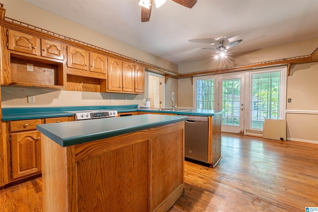 kitchen featuring stainless steel dishwasher, a ceiling fan, a kitchen island, a sink, and range