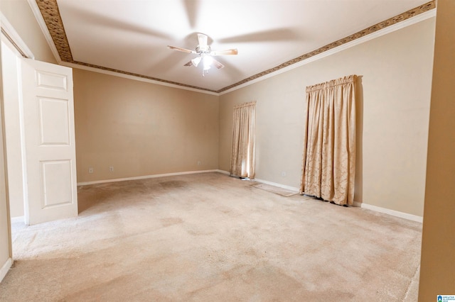 carpeted spare room with ceiling fan, crown molding, and baseboards