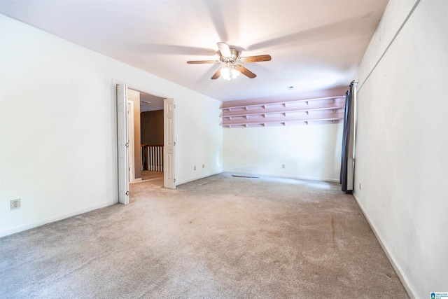 empty room with a ceiling fan, light carpet, and baseboards