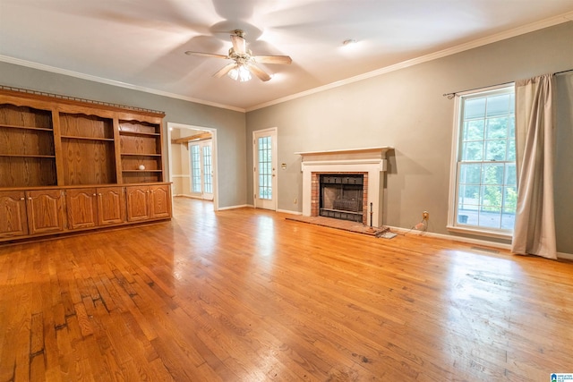 unfurnished living room featuring light wood-style flooring, ceiling fan, a brick fireplace, baseboards, and ornamental molding