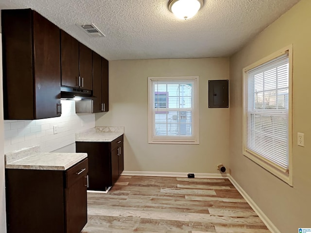1424 33rd St, Ensley, Birmingham, AL 35218 - kitchen featuring electric panel, dark brown cabinets, light wood-style flooring, a textured ceiling, and light countertops