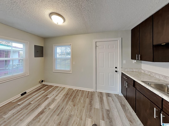 1424 33rd St, Ensley, Birmingham, AL 35218 - kitchen featuring electric panel, a textured ceiling, light wood-style flooring, dark brown cabinetry, and light countertops