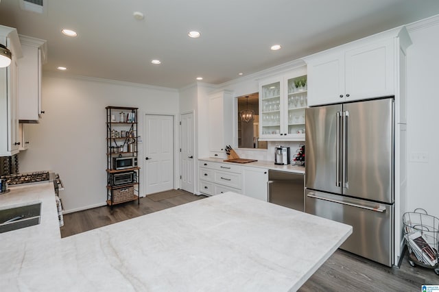kitchen featuring appliances with stainless steel finishes, dark wood-style flooring, crown molding, white cabinetry, and glass insert cabinets